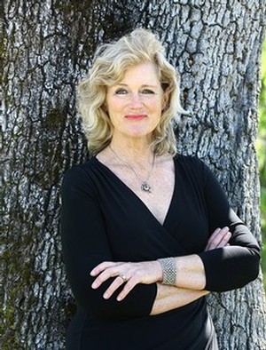 Portrait of winemaker Heidi Peterson Barrett, wearing a black dress, posed with a large oak tree