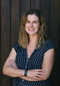 Professional headshot of Chelsea Barrett posed against a cellar door