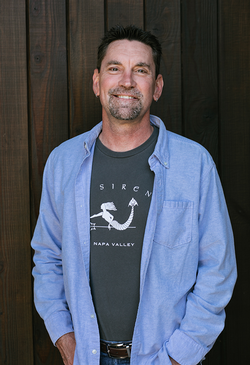 Professional headshot of David Schulze posed against a cellar door