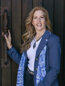 Professional headshot of Laurie Wolfe posed against a cellar door