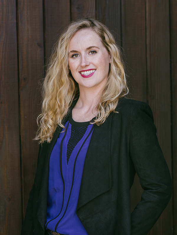 Professional headshot of Remi Barrett posed against a cellar door